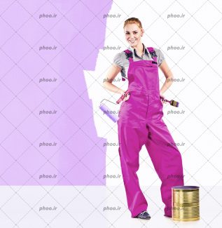 عکس با کیفیت زن با شلوار پیشبندی به رنگ بنفش و قلمو و غلتک در دست و دیوار بنفش در کنارش