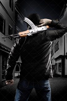 عکس با کیفیت کلاشینکف در دست مرد با کت مشکی و شلوار جین و ایستاده در وسط کوچه تاریک
