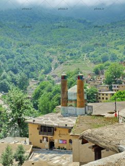 عکس با کیفیت مسجد تاریخی و قدیمی در روستایی زیبا در بالای کوه هایی با درختان سر سبز بر روی آن
