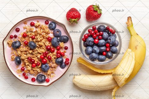 عکس با کیفیت بلوبری و آلبالو و توت فرنگی و موز در ظرف غلات صبحانه