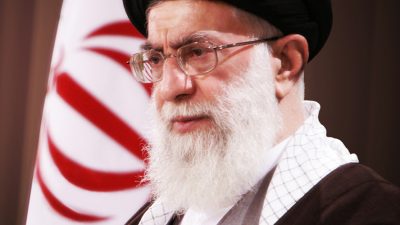 عکس با کیفیت پرچم ایران در کنار مقام معظم رهبری در زاویه سه رخ با عبا و عمامه مشکی