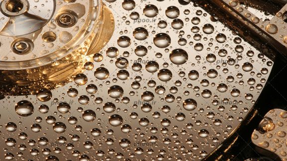 عکس با کیفیت نمای نزدیک از هارد دیسک کامپیوتر و قطرات آب بر روی صفحه هارد دیسک