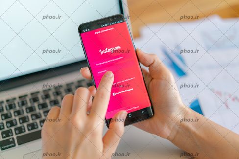 عکس با کیفیت مرد در حال نصب اینستاگرام و لپ تاپ در مقابلش