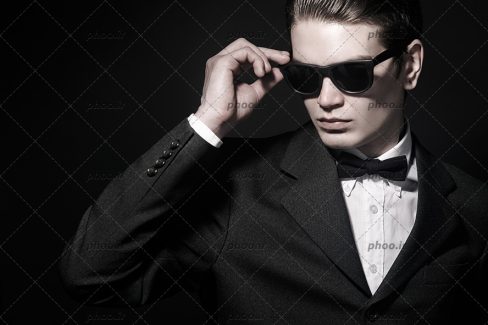 عکس با کیفیت مرد با کت مشکی و همراه پاپیون مشکی و عینک دودی بر روی چشم