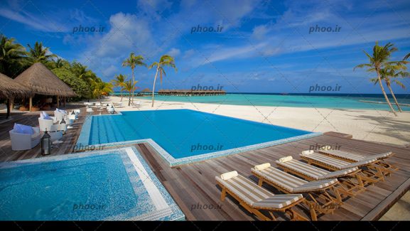 عکس با کیفیت استخر در ساحل همراه با تجهیزات و دریا با آب زلال در دور دست ها