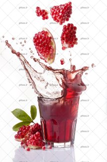 عکس با کیفیت سقوط اسلایس های انار در آب انار در اخل لیوان در پس زمینه سفید