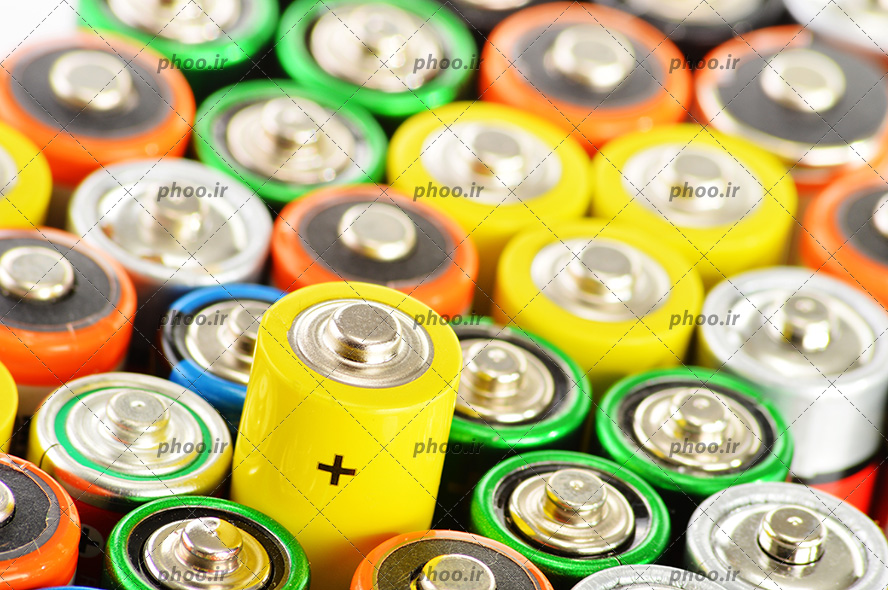 عکس با کیفیت باتری های قلمی رنگارنگ در کنار یکدیگر و بیرون آمدن یکی از آن ها و نمایان شدن نشانه مثبت آن