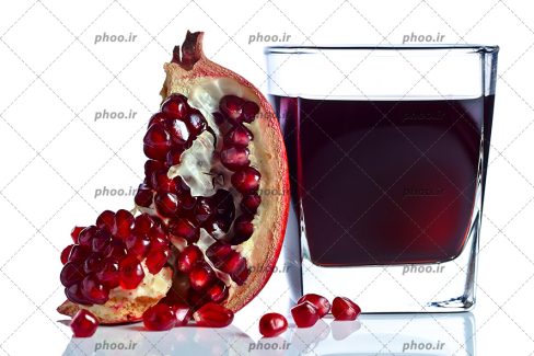 عکس با کیفیت آب انار در لیوان شیشه ای در کنار اسلایس انار