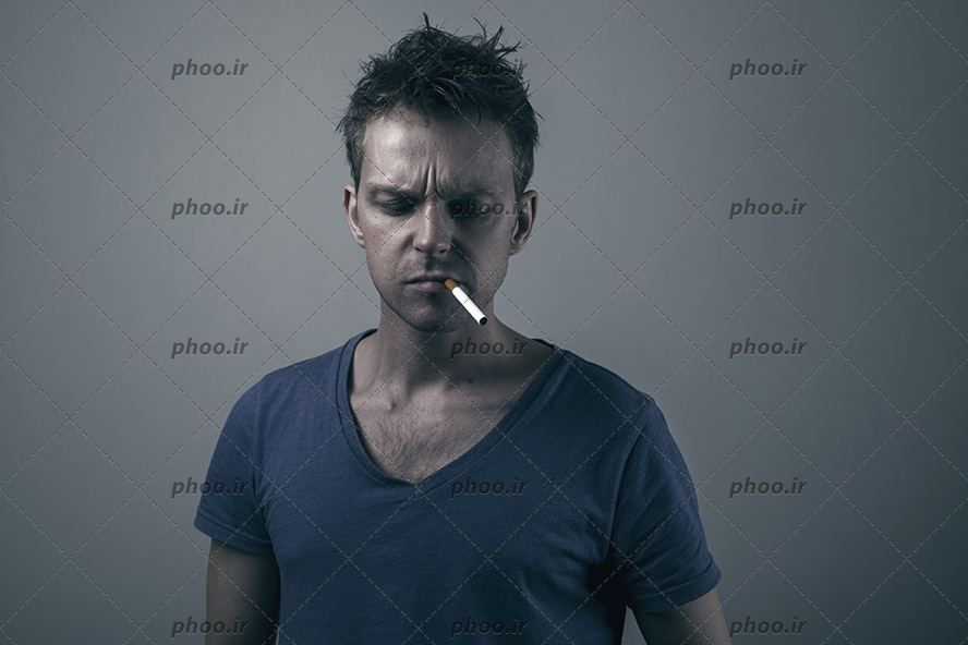 عکس با کیفیت مرد با تیشرت مشکی و سیگار بر لبان او و اخم بر چهره او و پس زمینه مشکی در پشت او