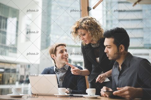 عکس با کیفیت زن و مرد در حال برسی و صحبت با یکدیگر و استفاده از لپ تاپ