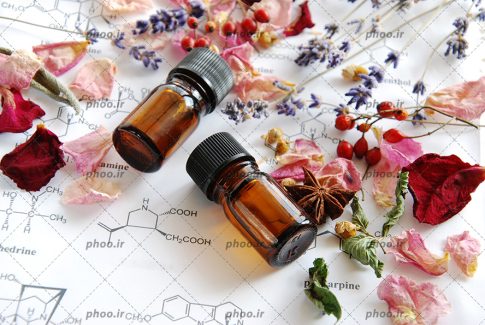 عکس با کیفیت شیشه های قهوه ای و گل های خشک شده بر روی فرمول شیمی نوشته شده بر روی برگه