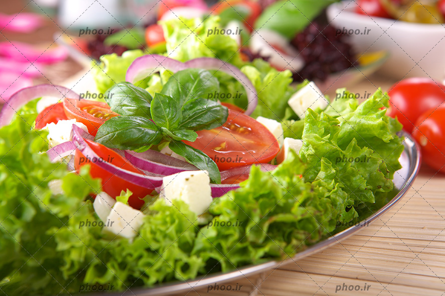 عکس با کیفیت پنیر های نگینی شده بر روی سالاد و تزیین شبیه یک گل بر روی سالاد با پیاز و گوجه