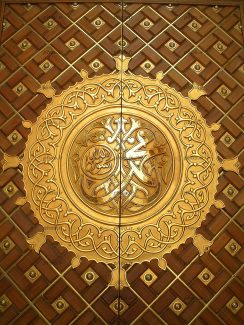 عکس با کیفیت شمسه ای زیبا به رنگ طلایی طلای کاری شده بر روی چوب زیبا و نام محمد (ص) در وسط شمسه