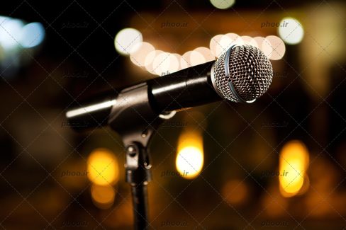 عکس باکیفیت تصویر میکروفون از نمای نزدیک و در پس زمینه نور های محو شده