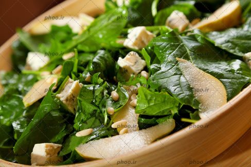 عکس با کیفیت ظرف چوبی و در آن سالاد سبزی و سیب و جو از نمای نزدیک
