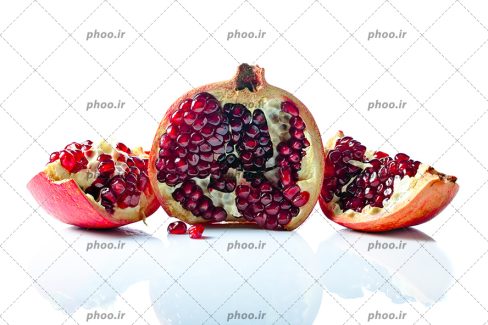 عکس با کیفیت انار اسلایس شده و اسلایس هایش در دو طرفش در پس زمینه سفید