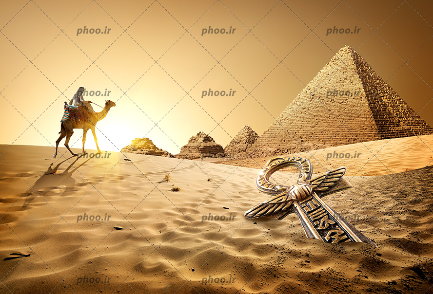 عکس با کیفیت کلید آنخ بر روی ماسه های کویر و مرد بر روی شتر در حال رفتن به سوی اهرام ها