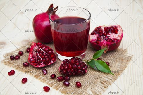 عکس با کیفیت لیوان آبمیوه در کنار انار و نیمه ی انار