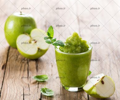 آب سیب همراه با سیب سبز تازه روی میز چوبی