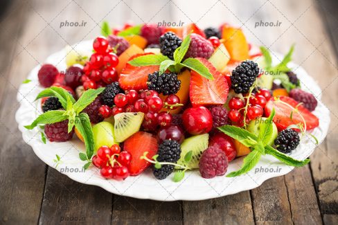 بشقاب میوه های تابستانی شامل تمشک کیوی توت فرنگی و…با تزئین نعناع