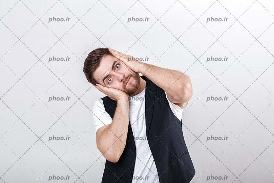 عکس مردی با تی شرت سفید و جلیقه مشکی که از سردرد کلافه شده و با هر دو دست سر خود را گرفته است