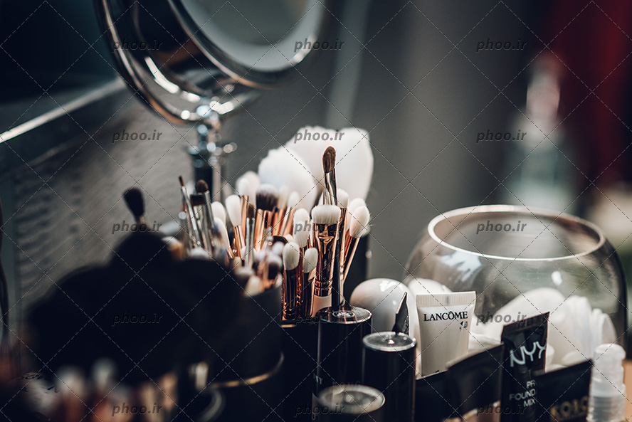 عکس تعدادی براش و قلم مو آرایشی و آینه پایه دار و لوازم آرایش و میکاپ لاکچری