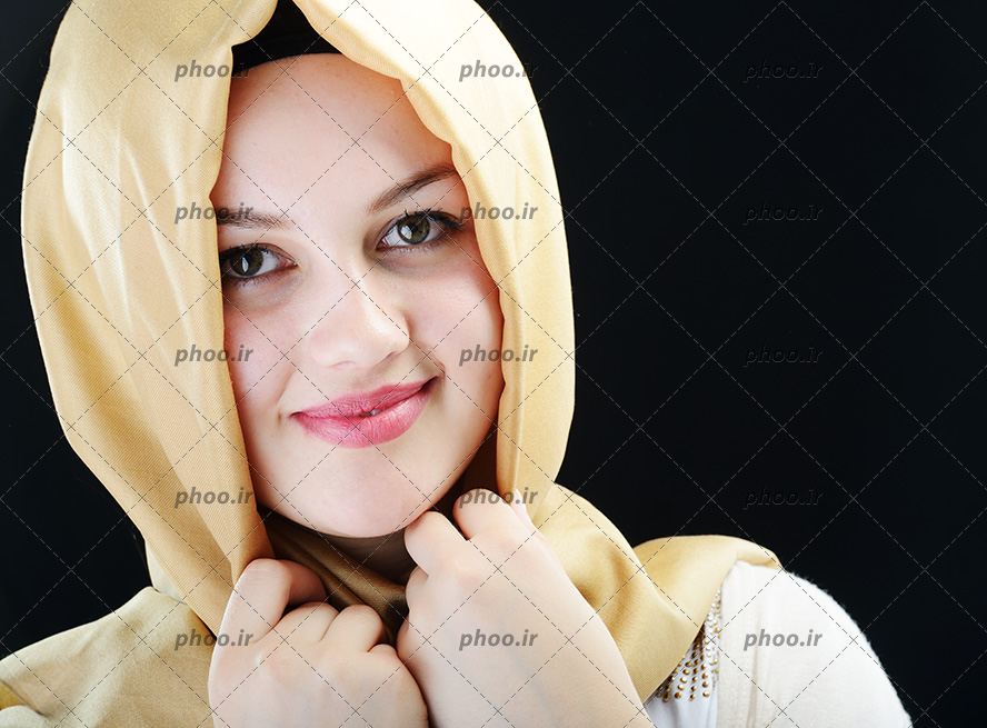 عکس خانم با حجاب با شال زرد که شال خود را با دست گرفته و لبخند میزند
