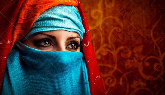 عکس یک خانم با حجاب با شال های آبی و قرمز که صورت خود را پوشانده است و به اطراف نگاه می کند