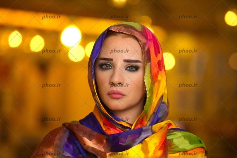 عکس با پس زمینه زرد و نارنجی یک خانم با شال طرح آبرنگی و خط چشم آبی