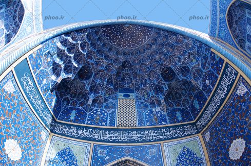 عکس سقف یک مسجد با کاشی کاری های آبی و نوشته های قرآنی روی آن