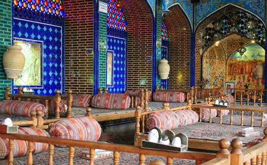 عکس یک رستوران سنتی با معماری جالب و کاشی کاری زیبا و تخت های چوبی