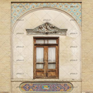 عکس یک پنجره چوبی با پرده سفید که بالای آن با گل های زیبا روی گچ تزئین شده و پایین آن با کاشی های رنگی