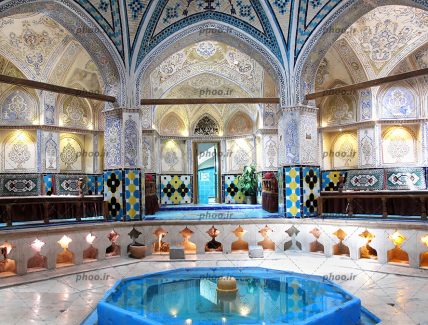 عکس یک حمام قدیمی با معماری جالب و نقش و نگار های زیبا و تخت هایی برای رختکن حوضچه آب و آتشدان های اطراف حوض