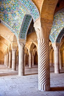 عکس یک معماری زیبا از یک مسجد با کاشی و آجر و ستون های پیچ دار وسط آن