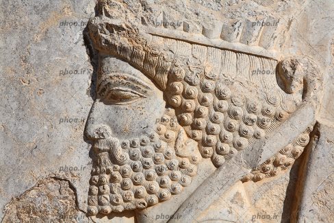 عکس نقش برجسته روی سنگ که با تراش کاری ایجاد شده است از سرباز با موهای فرفری و کمانی که دارد