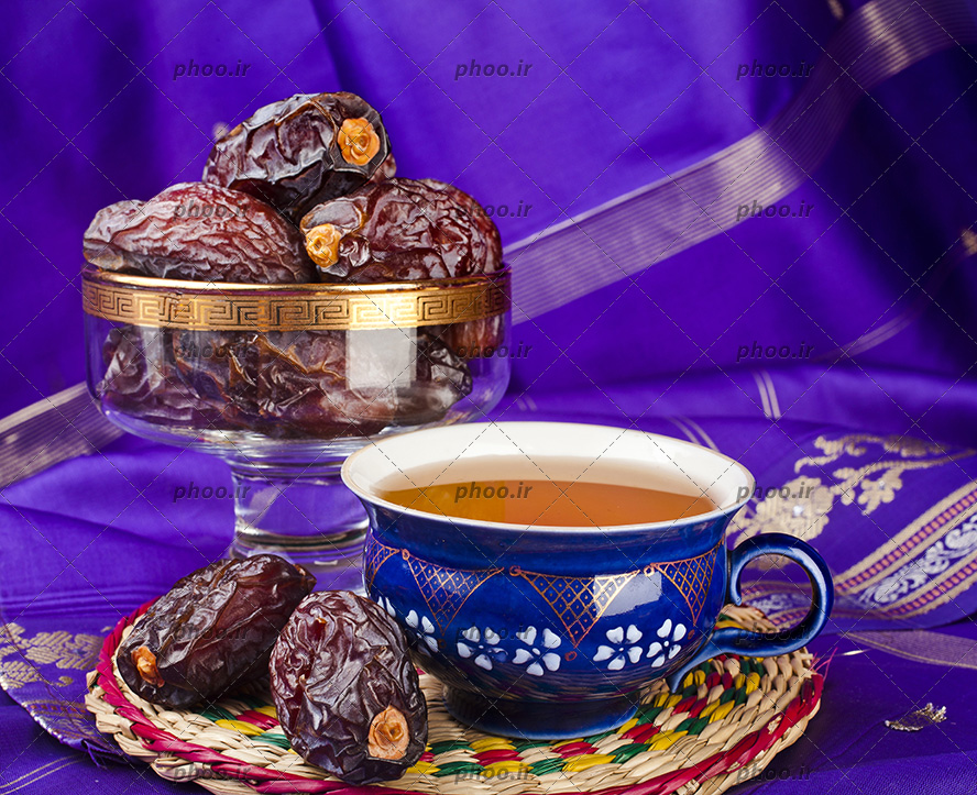 عکس یک قندان از خرما با یک استکان چای به رنگ آبی