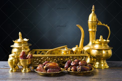 عکس دو بشقاب از خرما و یک قوری و قندان طلایی