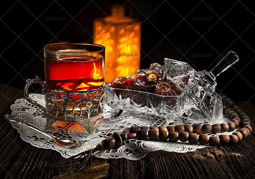 عکس یک استکان چای و یک قندان از خرما و یک تسبیح کنار آن