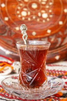 عکس یک استکان چای روی نعلبکی و یک قاشق داخل آن