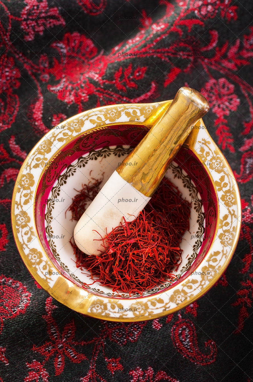 عکس یک هاون که در آن زغفران است و دسته هاون برای سابیدن زعفران