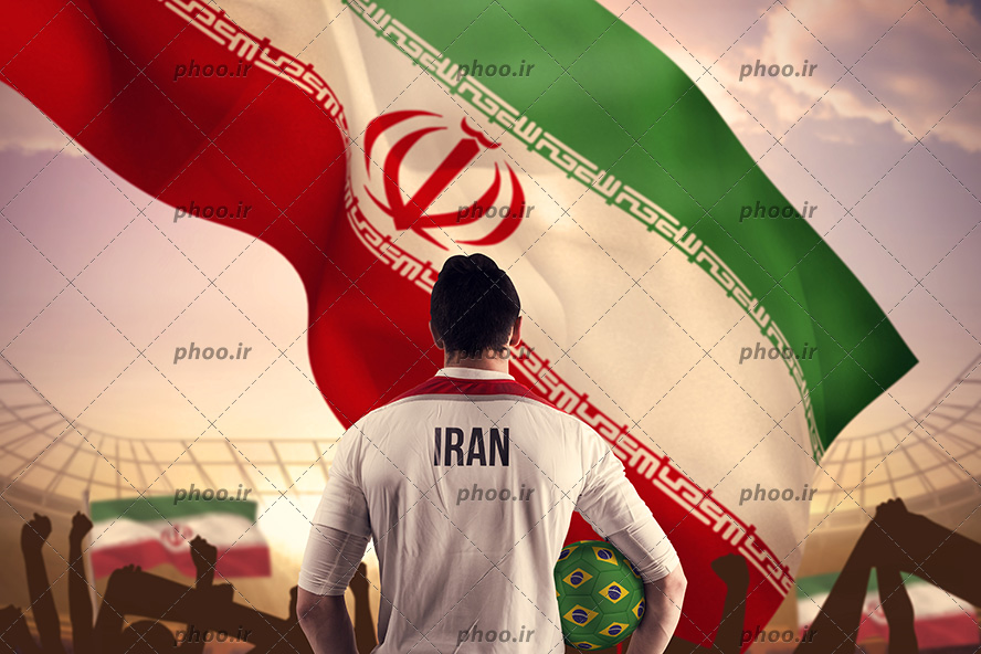 عکس یک مرد رو به پرچم برافراشته ایران که یک توپ سبز در دست دارد