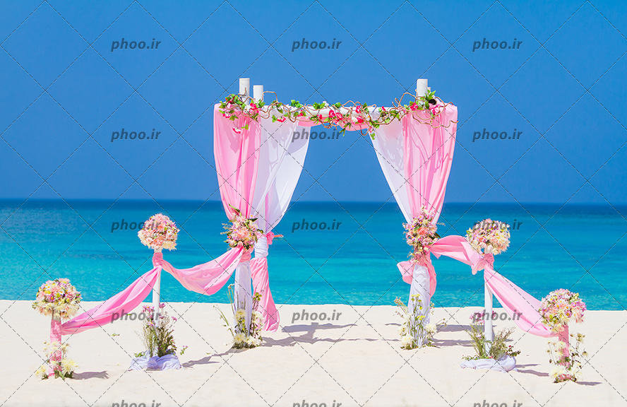 عکس یک ساحل که در آن با پارچه صورتی و گل دری به سوی دریا درست شده