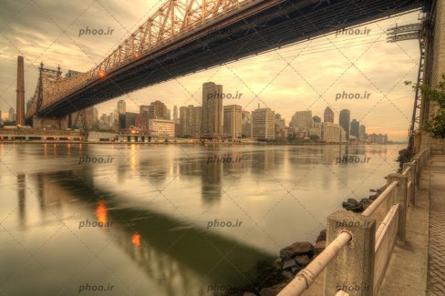 عکس کشور نیویورک با ساختمان بلند پل زیبا و دریا پر آب با آسمان ابری