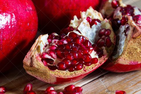 انار به همراه انار نصف شده در پیش زمینه چوبی