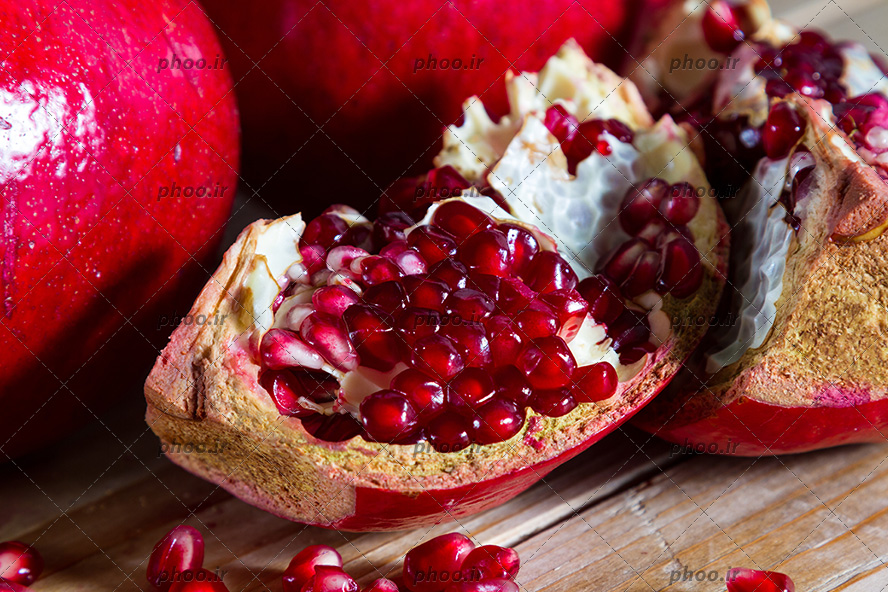 انار به همراه انار نصف شده در پیش زمینه چوبی