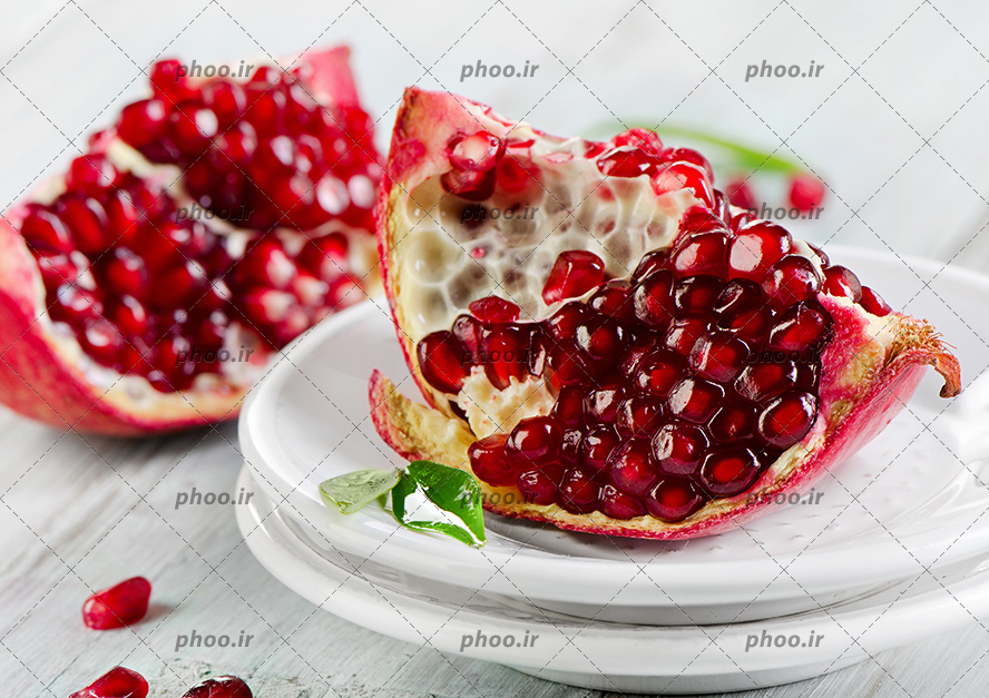 انار نصف شده در ظرف سفید در پیش زمینه سفید