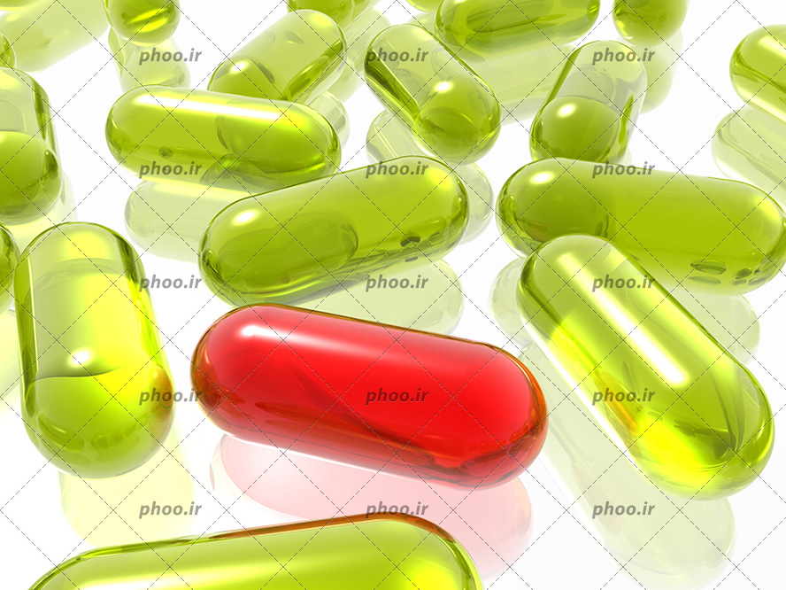 کپسول های دارویی به رنگ سبز و یک عدد کپسول قرمز در پیش زمینه سفید