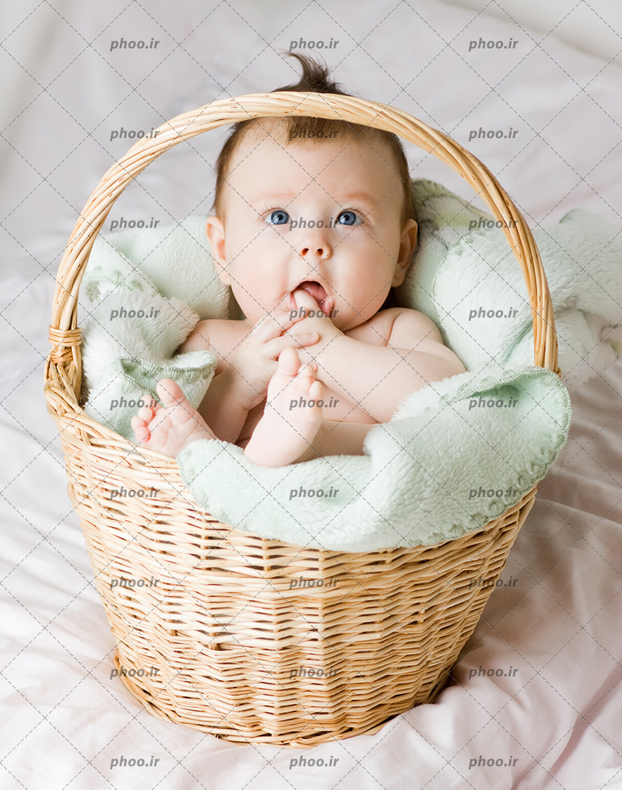 عکس یک کودک روی پتو داخل سبد حصیری