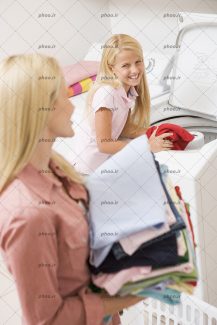 عکس یک مادر و درختر در حال شستن و تا زدن لباس