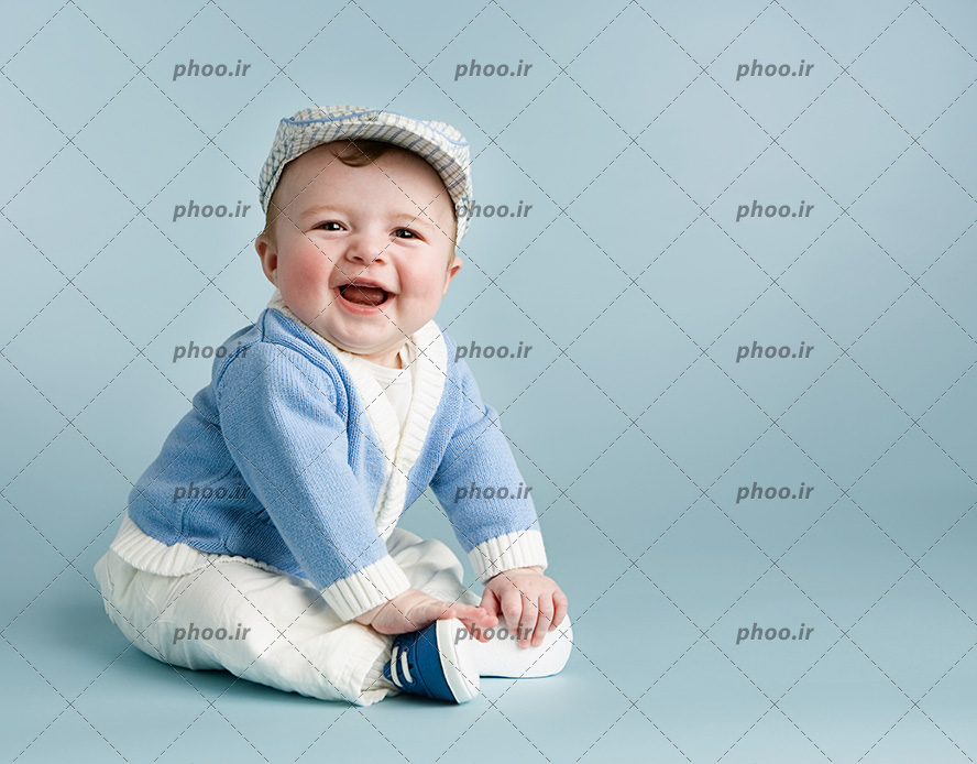 عکس یک کودک خندان با کلاه و لباس بافتنی آبی